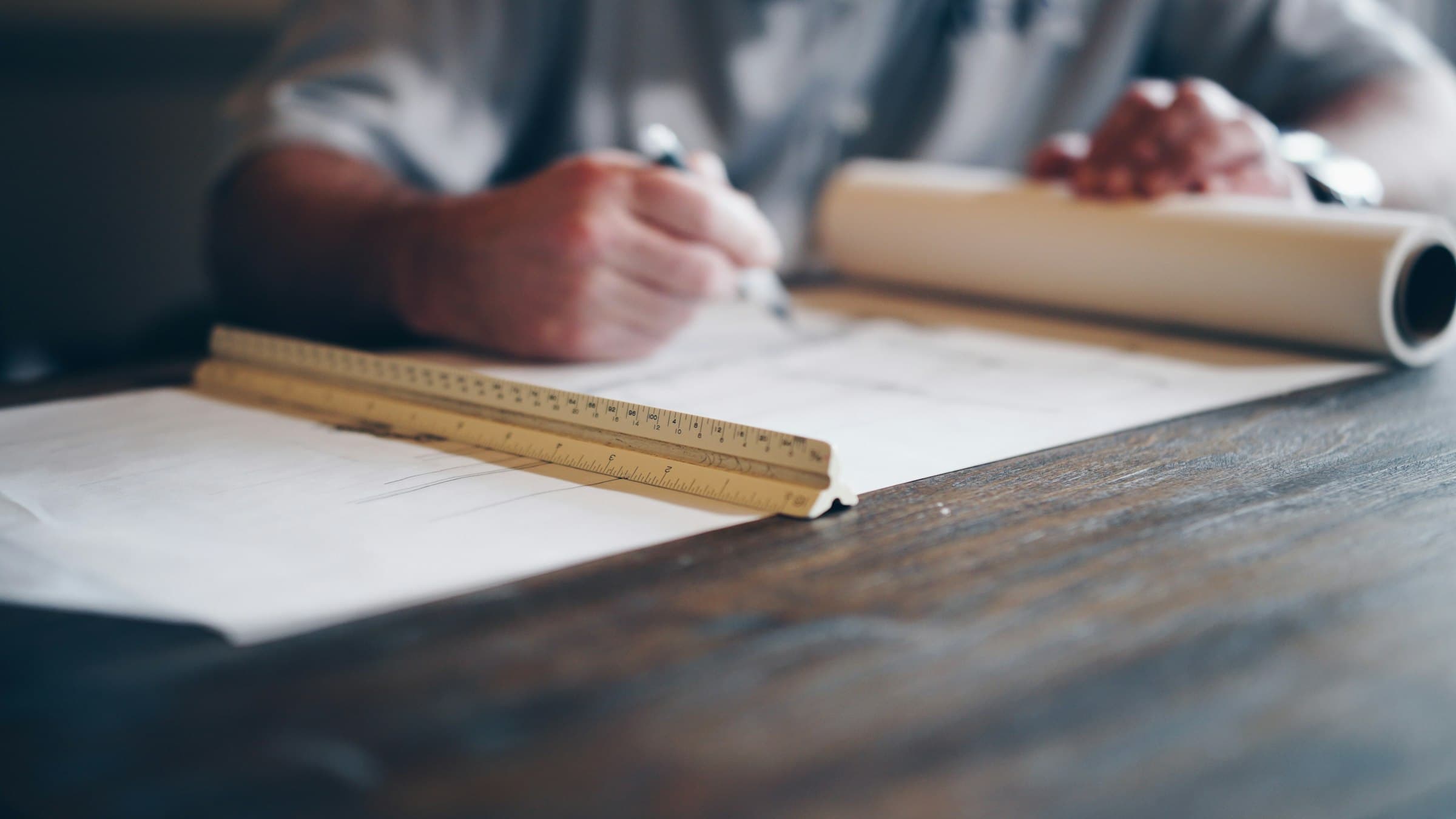 Een vergunningtekening wordt met de hand ingetekend op een werktafel